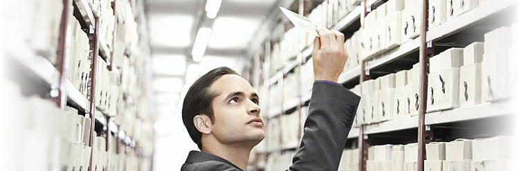 Image of a man looking at a microfiche, with shelves that are full of microfiche in the background. The image relates to this blog article, as the article describes how capturing the data from a microfiche can save and protect the data. We offer a service where we capture and convert your microfiche data to a digital file with our microfiche scanning services in London and throughout the UK.