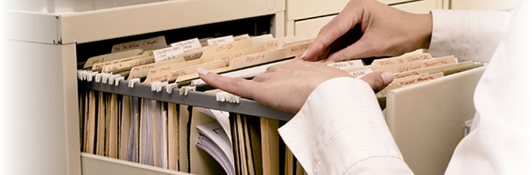 An image of a person searching through documents in a filing cabinet. The image relates to the blog article, as the article gives the user information on how scanning docuemnts to a digital file can save time in various departments in all types of organisations in London and all over the UK. Our document scanning services in London and the UK offer a cost effective solution to help organisations go paper free.